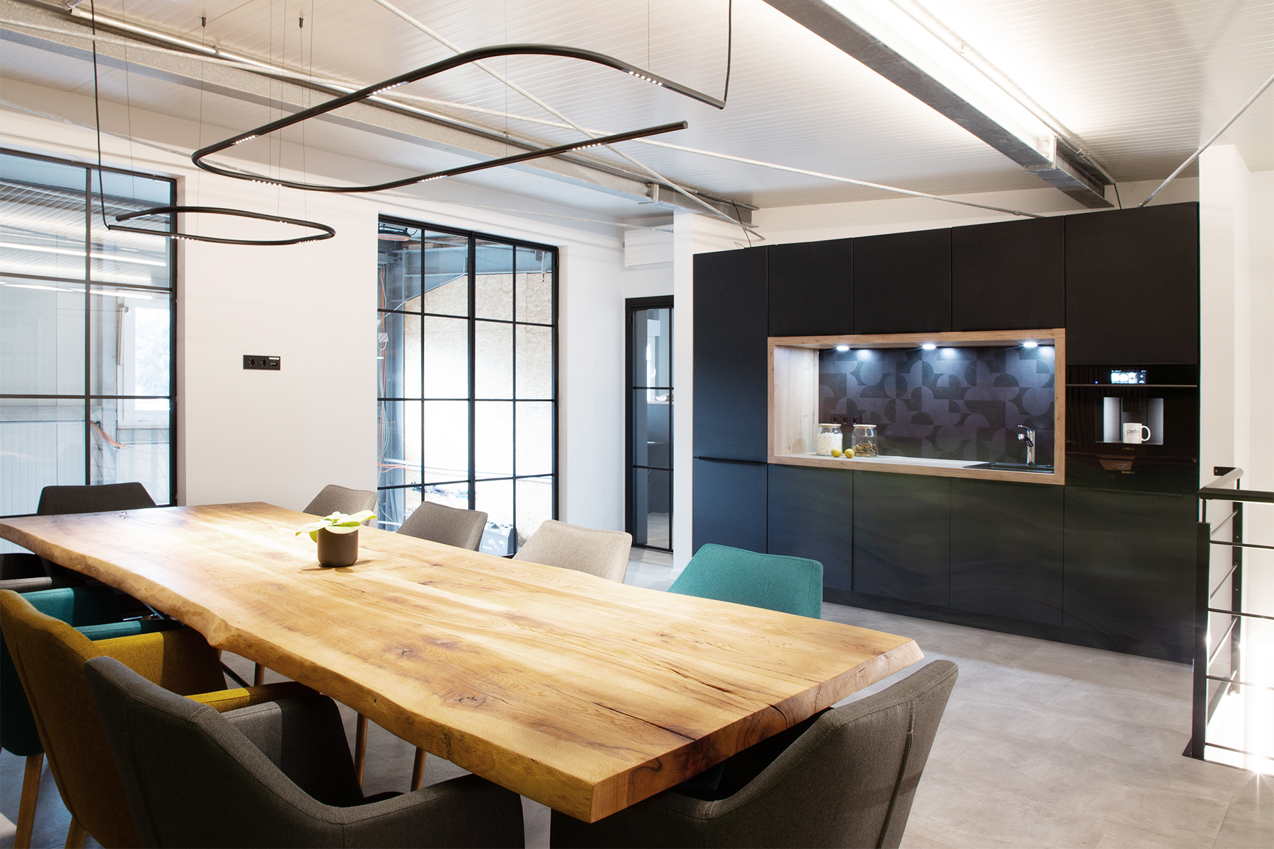 Moderner Besprechungsraum der Petri Heizung & Sanitär GmbH in Mühlheim am Main mit anthrazitfarbenen Möbeln, Betonboden, großem Holztisch und Holz-Akkustikpanels und dekorativer Mooswand.
