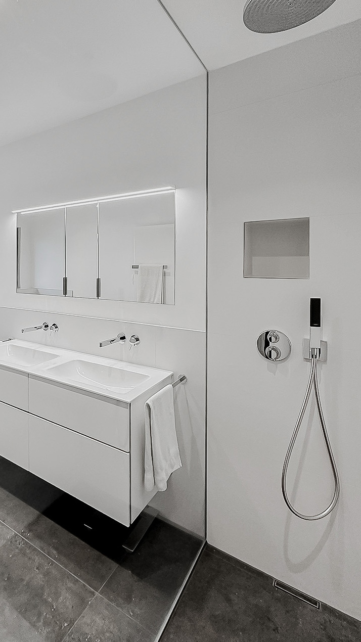 Helles Badezimmer mit anthrazitfarbenen Bodenfliesen, weißen Wandfliesen, barrierefreier Dusche mit Regenduschsystem, Badewanne, Doppelwaschtisch mit Chrom-Armatur, Spiegel, Toilette und modernen Sanitärinstallationen, elegantes und funktionales Design. Petri Heizung & Sanitär, Mühlheim am Main.