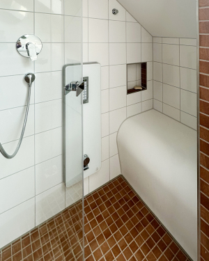 Kleines Badezimmer groß gedacht mit Holzfliesenboden, weißen Wandfliesen, Waschtisch mit Chrom-Armatur, weißem Waschtischunterschrank, Hänge-WC und Dampfdusche – funktionales und stilvolles Design. Petri Heizung &amp; Sanitär, Mühlheim am Main.