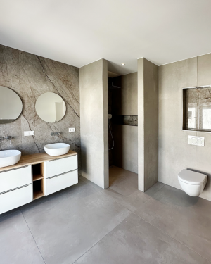 Elegantes Badezimmer mit bodentiefer Dusche mit Regenduschsystem, Doppel-Aufsatzwaschbecken mit Spiegel, Badewanne, sandfarbenen Bodenfliesen und beige/braune Wandfliesen in Marmoroptik. Petri Heizung &amp; Sanitär, Mühlheim am Main