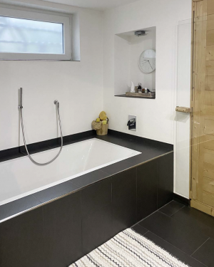 Zeitloses Badezimmer mit schwarzen Bodenfliesen, weißen Wandfliesen, Badewanne, barrierefreier Dusche mit Regenduschsystem, Toilette, Bidet und Wandheizkörper für elegantes und modernes Design. Petri Heizung &amp; Sanitär, Mühlheim am Main