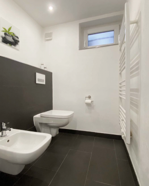 Zeitloses Badezimmer mit schwarzen Bodenfliesen, weißen Wandfliesen, Badewanne, barrierefreier Dusche mit Regenduschsystem, Toilette, Bidet und Wandheizkörper für elegantes und modernes Design. Petri Heizung &amp; Sanitär, Mühlheim am Main