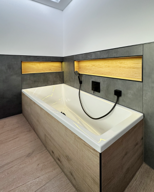 Modernes Badezimmer mit anthrazitfarbenen Wandfliesen, Holzfliesenboden, Waschtischunterschrank aus Holz, großem Doppelwaschtisch, schwarz-matte Armaturen, Toilette, Bidet, Badewanne und barrierefreier Dusche mit Regenduschsystem für stilvolles und funktionales Design.