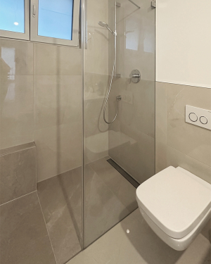 Helles Badezimmer mit barrierefreier Dusche, Toilette, Waschtisch mit Chrom-Armatur und modernen Sanitärinstallationen, elegantes und funktionales Design. Petri Heizung &amp; Sanitär, Mühlheim am Main.