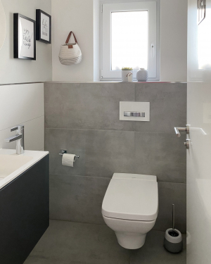 Modernes Gäste-WC mit Betonfliesen und weißen Wandfliesen, ausgestattet mit Handwaschbecken, anthrazitfarbenem Waschtischunterschrank und Dusch-WC für funktionales und komfortables Design im kleinen Raum. Petri Heizung &amp; Sanitär, Mühlheim am Main.