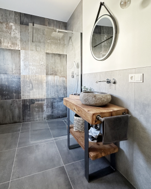 Modernes Gästebad mit Wandfliesen in Rostoptik, anthrazitfarbenen Bodenfliesen, Waschtischunterschrank aus Holz, Aufsatz-Waschbecken aus Granit und barrierefreier, ebenerdiger Dusche mit Regenduschsystem – stilvolles und funktionales Design. Petri Heizung &amp; Sanitär, Mühlheim am Main.