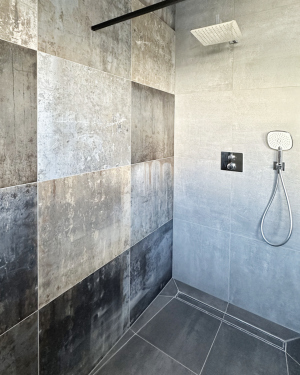Modernes Gästebad mit Wandfliesen in Rostoptik, anthrazitfarbenen Bodenfliesen, Waschtischunterschrank aus Holz, Aufsatz-Waschbecken aus Granit und barrierefreier, ebenerdiger Dusche mit Regenduschsystem – stilvolles und funktionales Design. Petri Heizung &amp; Sanitär, Mühlheim am Main.